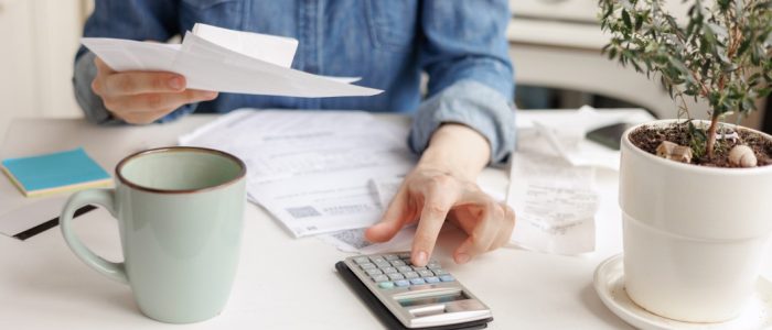 woman-sits-at-the-kitchen-table-and-pays-utility-bills-and-writes-checks-a-beautiful-young-european_t20_Z6LyYj